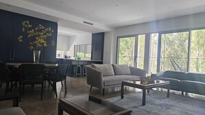 A modern living room with a sofa, coffee table, and dining area. - Sanctuary on the Creek (Sanctuary Point)