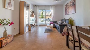 Un salon comprenant un canapé, une table à manger, un téléviseur et une grande fenêtre.