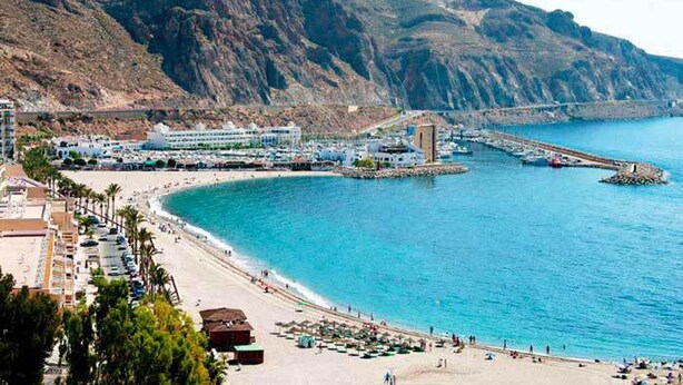 Une ville côtière dotée d’une plage, d’un port de plaisance et d’un pont.