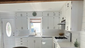 A modern kitchen with white cabinets, a wooden dining table, and a built-in stove.