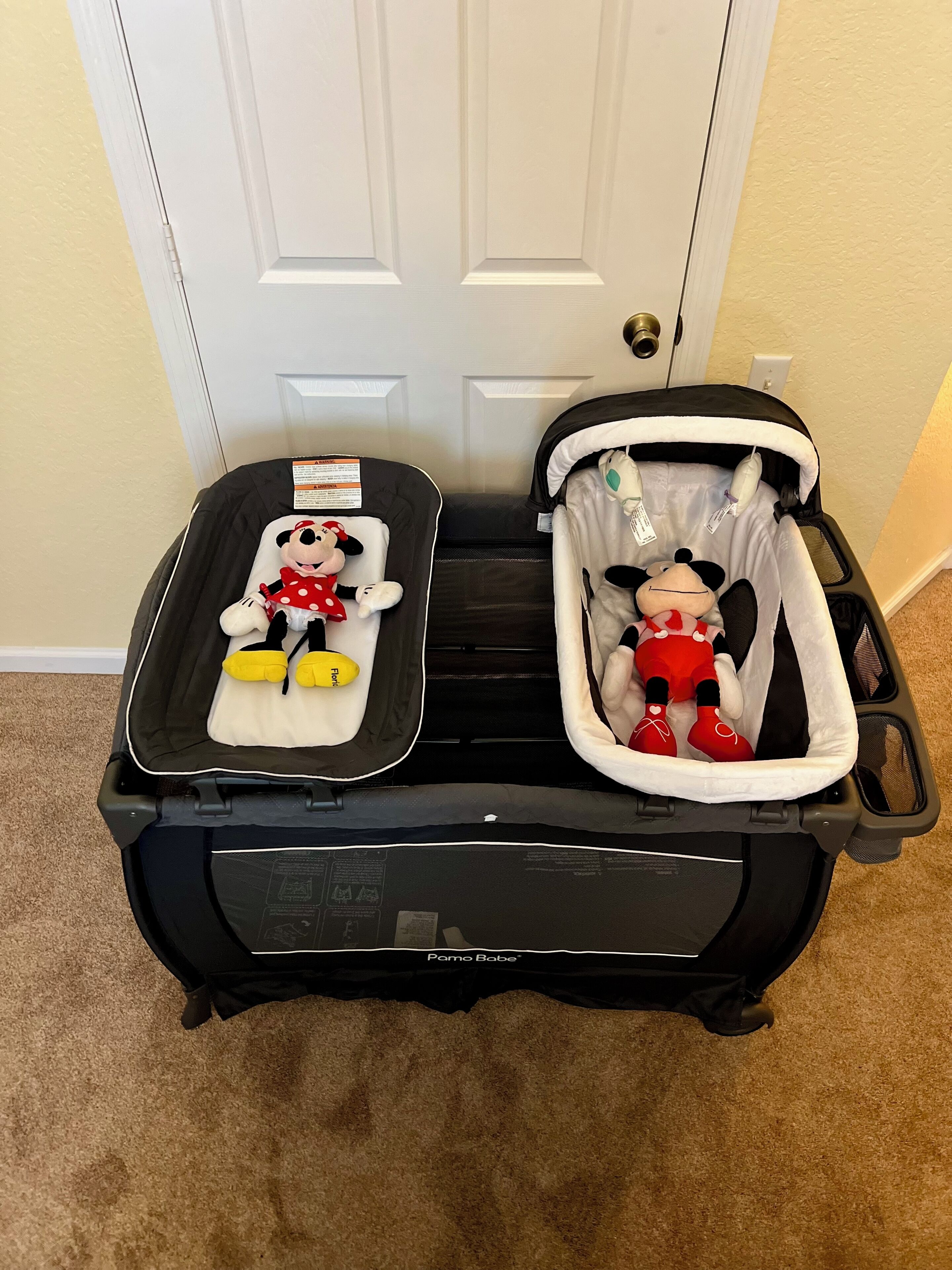 Uma mala preta com dois bichos de pelúcia do Mickey Mouse lá dentro, um de cada lado.