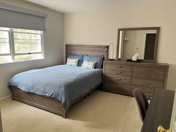 Un dormitorio con cama, cómoda, espejo y ventana.