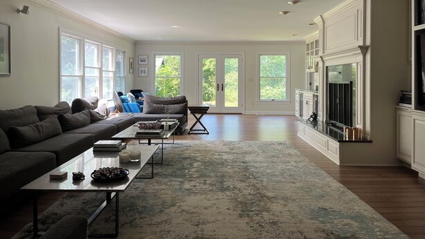 A spacious living room with a large window, a sofa, a coffee table, and a fireplace.