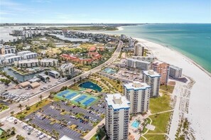 Un hotel costero con varios edificios altos, una playa y un puerto deportivo.