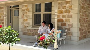 A stone building with a porch, a bench, and a small tree with flowers. - Country Style Louisa - Gawler  (Gawler)