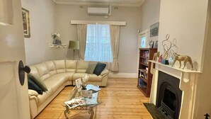 A living room with a sofa, coffee table, fireplace, and bookshelves. - Country Style Louisa - Gawler  (Gawler)