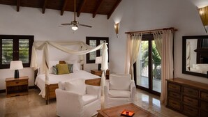 A spacious bedroom with a canopy bed, two bedside tables, a nightstand, a wooden dresser, and a large window with curtains.