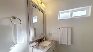 A bathroom with a white vanity, a large mirror, and two towels hanging on the wall. - Cozy Studio in beautiful SugarHouse, King Bed, WiFi, AC (Salt Lake City)