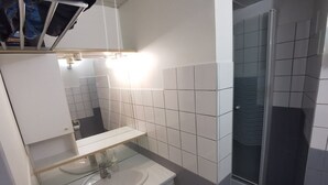 Ein Badezimmer mit weißem Waschbecken, Spiegel und Fliesen.