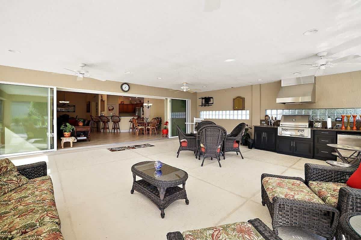 A spacious living area with wicker furniture, a glass coffee table, and a kitchen area with modern appliances.