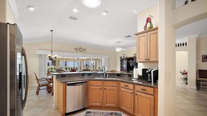 A spacious kitchen with wooden cabinets, a central island, and a dining area with chairs.