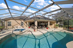 Une piscine intérieure couverte avec un toit en verre, des chaises longues et un espace patio.