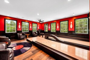 A bowling alley with wooden floors, leather chairs, and a pinsetter.