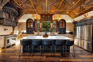 A spacious kitchen with a large island, modern appliances, and a high ceiling with wooden beams.
