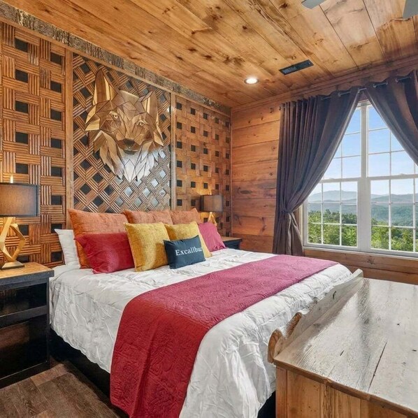A wooden-paneled bedroom with a bed, pillows, a nightstand, and a window with curtains.