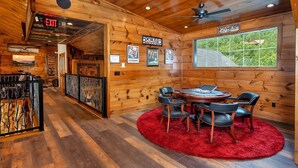 A wooden interior with a poker room, a round table with chairs, and a large window with a view. - Excalibur: Pickleball, Duck Pin Bowling, Indoor Pool, 9 Hole Golf (Sevierville)