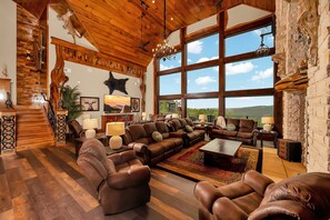 A spacious living room with a large window, leather sofas, and a fireplace.