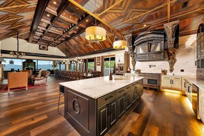 A spacious kitchen with a large island, modern appliances, and a high ceiling with exposed beams. - Excalibur: Pickleball, Duck Pin Bowling, Indoor Pool, 9 Hole Golf (Sevierville)