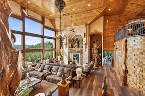 A spacious living area with a fireplace, leather sofas, and a large window offering a view of the outdoors.