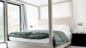 Une chambre à coucher moderne avec un lit à baldaquin, une grande fenêtre avec des rideaux et une lampe de chevet.