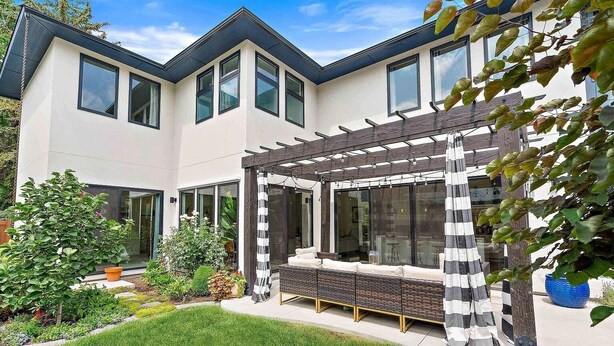 Une maison moderne à deux étages, dotée d’un patio couvert et d’un jardin bien entretenu.