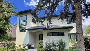 Une maison moderne à deux étages, dotée d’un toit plat, de grandes fenêtres et d’une pelouse bien entretenue.