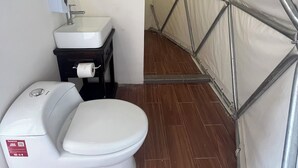 A bathroom with a toilet, sink, and mirror. - Glamping Cholula (San Pedro Cholula)