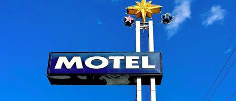 Un letrero de motel con una estrella y un cartel que dice 'MOTEL' contra un cielo azul despejado.