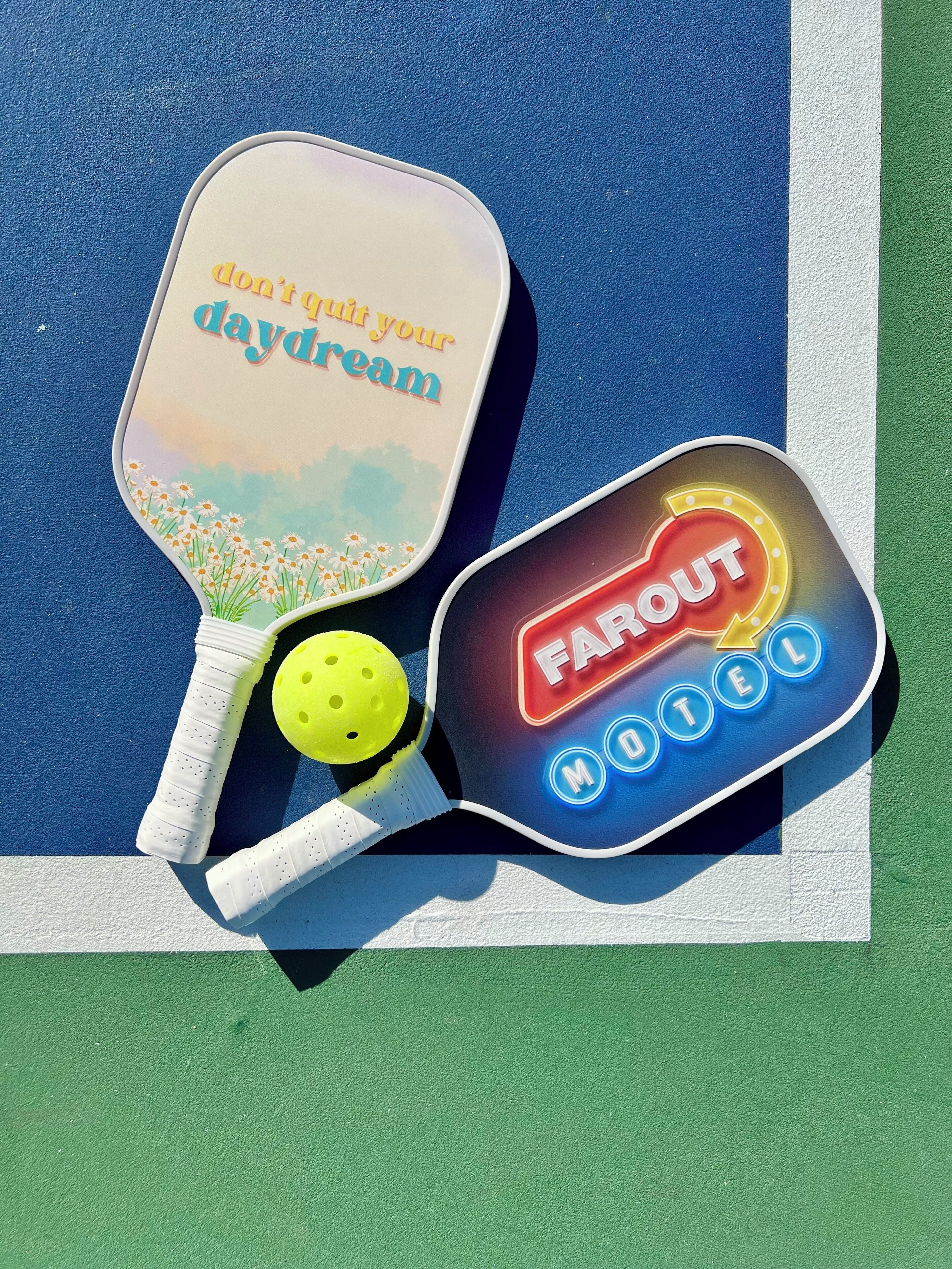 Two ping pong paddles with text on them and a yellow ball.