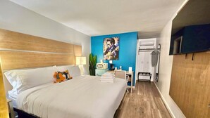 Een hotelkamer met een groot bed, een bureau, een stoel, een televisie en een garderobe.