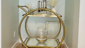 Une table d’appoint à plateau en verre, encadrée de doré, sur laquelle sont posés un vase et une petite plante, placée dans un couloir aux murs bleu clair et au plafond blanc.