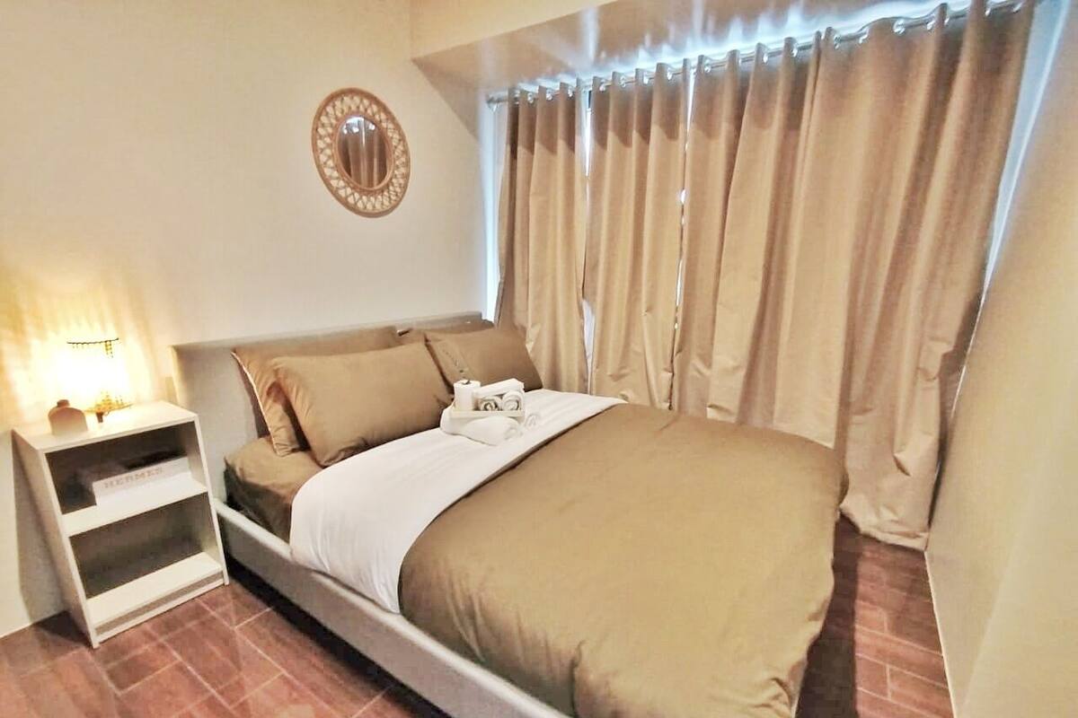 A neatly arranged bedroom with a bed, a bedside table, and a mirror on the wall.