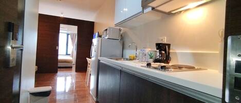 Una cocina moderna con armarios oscuros, una encimera blanca y un microondas empotrado.
