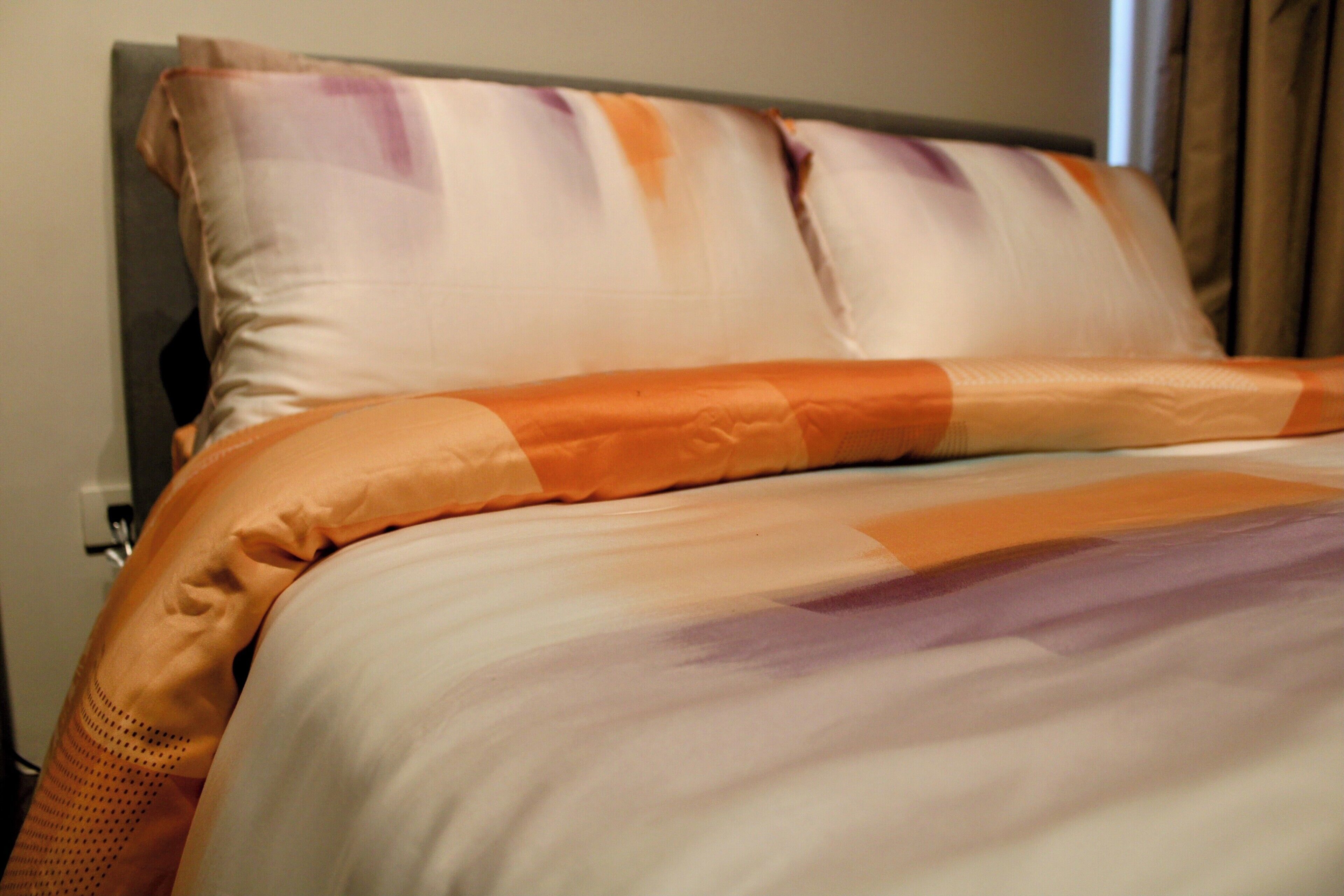 Una cama con manta y almohadas a rayas.