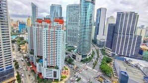 A high-rise building with a modern design, surrounded by other tall buildings and a busy street with vehicles. - Air Residences-CBD view  (Makati)