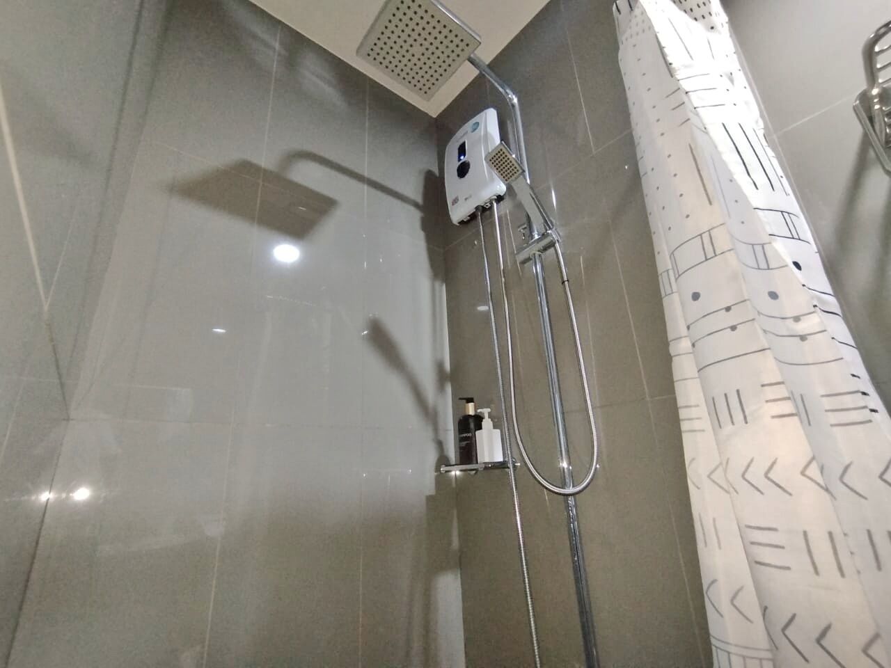 A modern shower with a handheld showerhead and a wall-mounted control panel.