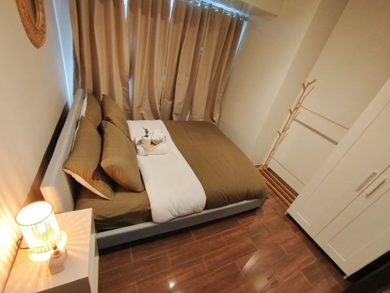 A compact bedroom with a bed, pillows, a bedside lamp, and a wardrobe.
