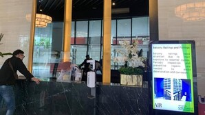 A reception area with a marble counter, large windows, and a sign about balcony railings and fittings. - Air Residences-CBD view  (Makati)