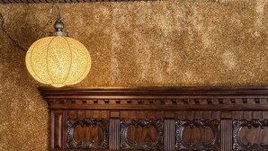 Una habitación con cabecera de madera, lámpara colgante y edredón estampado.