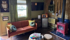 Una sala de estar acogedora con sofá, una mesita, televisión y una zona de cocina con estufa, además de un cartel de 'No Smoking'.