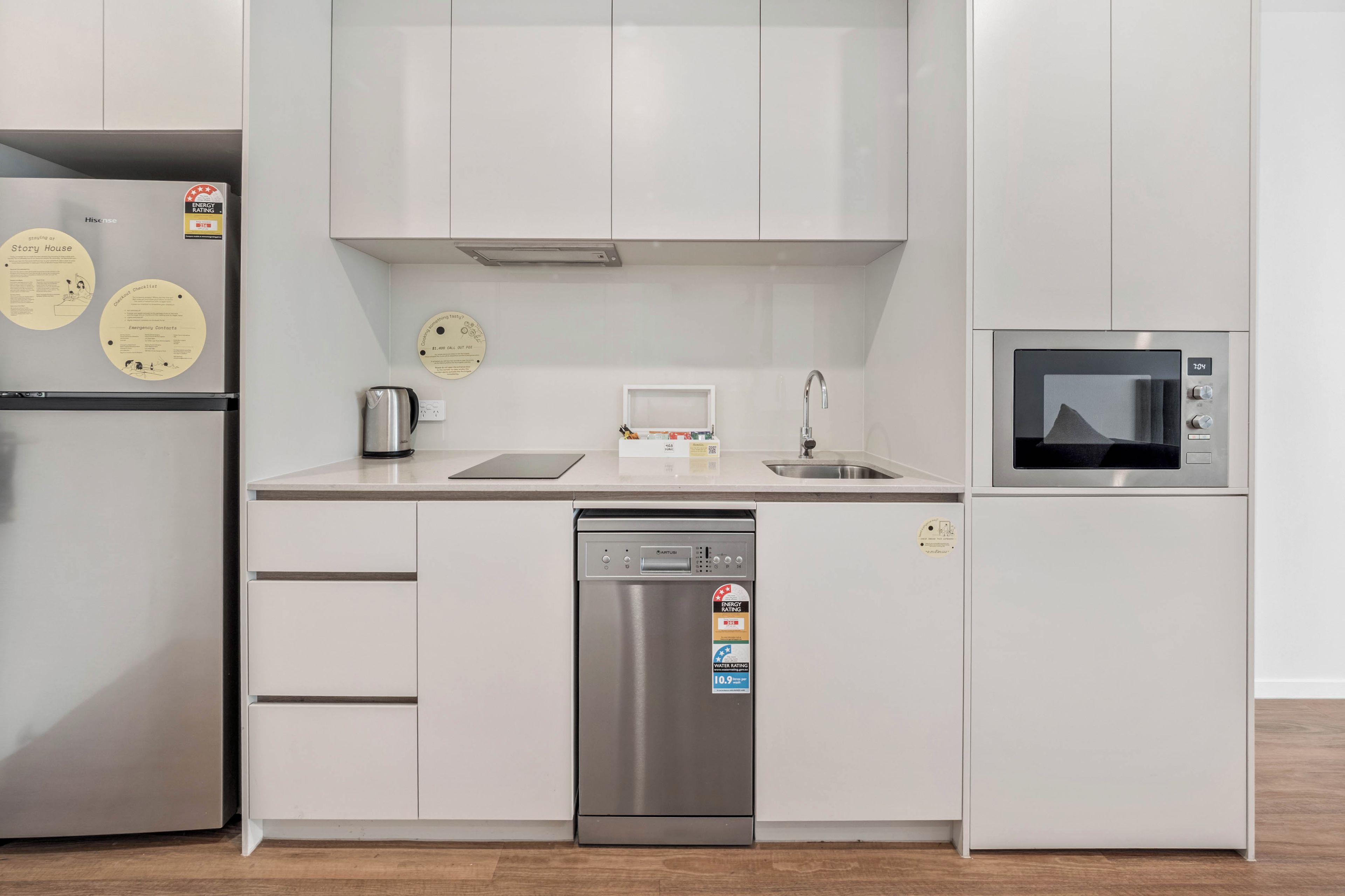 Una cocina moderna con lavavajillas de acero inoxidable, microondas y refrigerador.