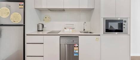 Una cocina moderna con lavavajillas de acero inoxidable, microondas y refrigerador.