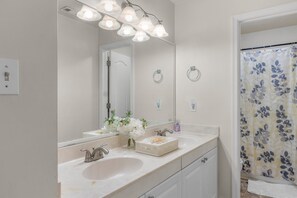Un baño con dos lavamanos, un espejo grande y una cortina de ducha con estampado floral.