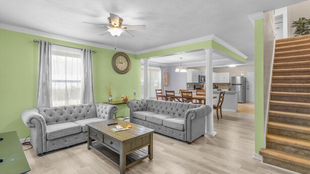 A living room with two grey sofas, a wooden coffee table, and a ceiling fan. A staircase is visible to the right. - Lovely Beach House -Ocean Duplex (Norfolk)