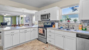 A modern kitchen with white cabinets, a stainless steel oven, a microwave, and a dishwasher. - Lovely Beach House -Ocean Duplex (Norfolk)