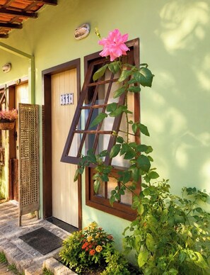 A building with a wooden door, a window with a grid pattern, and a number plaque.