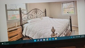 A bedroom with a bed, wooden dresser, and two windows. - confortable villa (New Carrollton)