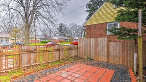 A backyard with a red brick patio, wooden fence, and houses in the background. - confortable villa (New Carrollton)