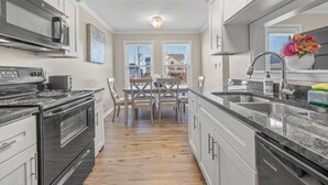 Una cocina moderna con una isla central, electrodomésticos de acero inoxidable y un comedor con vistas.