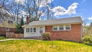 A single-story brick house with a front porch and a small front yard. - Comfortable villa (New Carrollton)